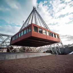 a long red boat suspended on to of a bridge