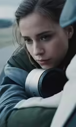 a young girl in green jacket with a black camera