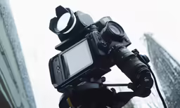 video camera attached to tripod on a tripod near a building