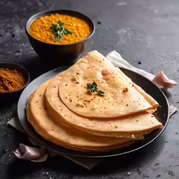 a plate topped with five pita bread next to bowls of hummus