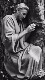 a statue is leaning against the tree and holding his hands together