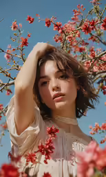 a woman posing beneath pink flowers