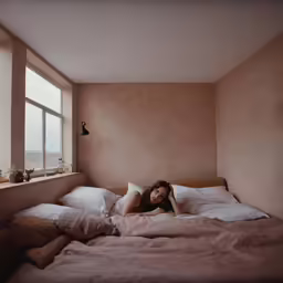 woman lying on a bed by the window