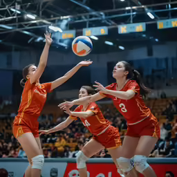 volley ball players in orange uniforms reaching for the ball