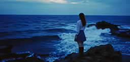woman standing at ocean shore looking into the sky