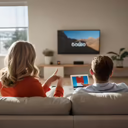 two people sitting on a couch watching television