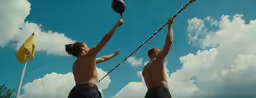 two men playing frisbee against blue cloudy sky