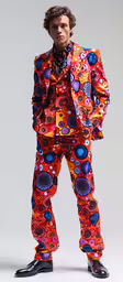 a man wearing an orange jacket and tie in front of a white background,a man in colorful clothes standing in front of a white background