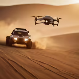 a car driving down the desert in front of a flying object
