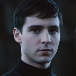 a young man with dark hair looking at the camera