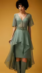 a woman is dressed in an elegant green gown and boots