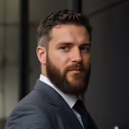 a man with a beard standing in front of a wall