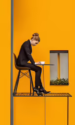 a person sitting at a table on a chair with a laptop