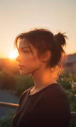a woman with her hair in a ponytail is looking off into the distance at sunset