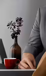 man in suit writing on piece of paper next to red coffee cup