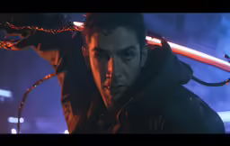 a young man in black jacket holding up a red object