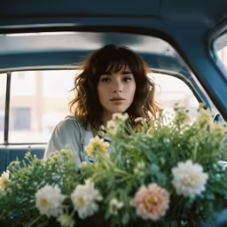 a young woman sits in the backseat seat of a blue car