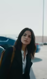 woman wearing black jacket with white shirt and brown purse walking down street