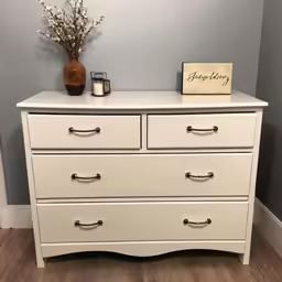a white dresser with flowers, candles, and a sign