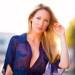 an attractive woman posing in a blue shirt,a close up of a woman with long hair and a blouse on