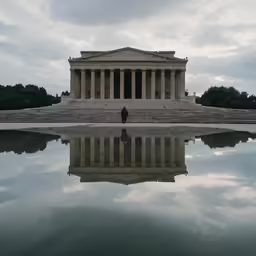 a tall monument surrounded by trees sitting in the middle of a lake