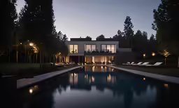 an outdoor house lit up at night with pool