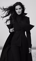 a woman in black coat and boots posing for a photo