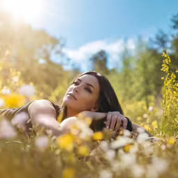 a woman laying down in the grass in front of some flowers