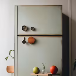 three apples, an orange and one apple sit on the edge of the table