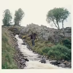 the man is walking on a hill by the water