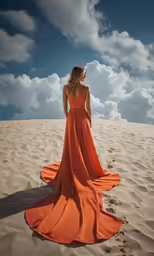 a woman in an orange dress is standing in the sand