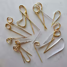many small, open scissors sit on a marble countertop