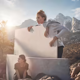 two woman in black and grey are posing against a wall