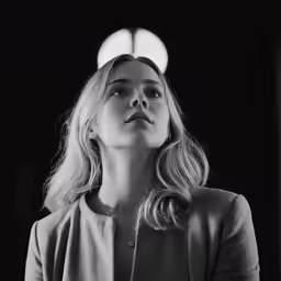 a black and white photo of a woman standing in front of a light