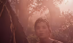 a woman with a brown top standing next to trees