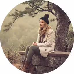 a beautiful woman sitting on a stone wall