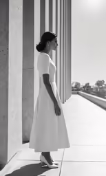 a woman in a dress standing by some pillars