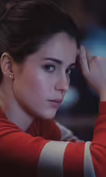 a young woman has her hands to her ear and holds a hand behind her head