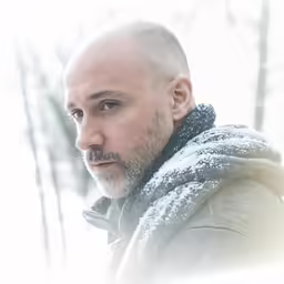man with bald hair looking to his left on snowy day