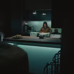 a woman standing at the counter of a kitchen