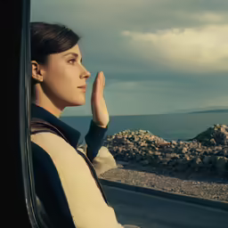 woman in a yellow and black sweater sitting on the side of a car