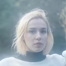 an attractive blonde woman with blue eyes standing