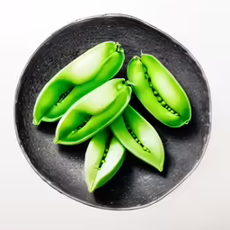 green beans sitting on a black plate with white border