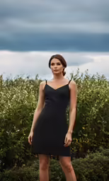 a beautiful young woman standing on a lush green field