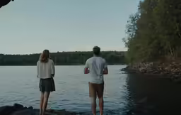 two people are looking out over water on rocks