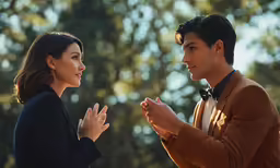 two people standing and clapping near some trees