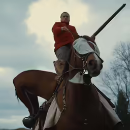 the young man is sitting on the horse and ready to throw the ball