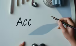 hands on the table writing the letter act with a pen and two crayons