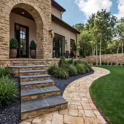 a brick building with steps leading up to a front yard