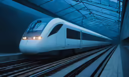 a white train going through a station under a blue sky